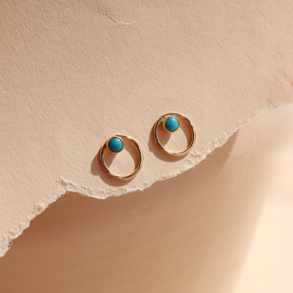 14k gold fill, circle hammered ear jacket that is paired with a 4mm turqouise stud, displayed on a cream backdrop in the sunlight 