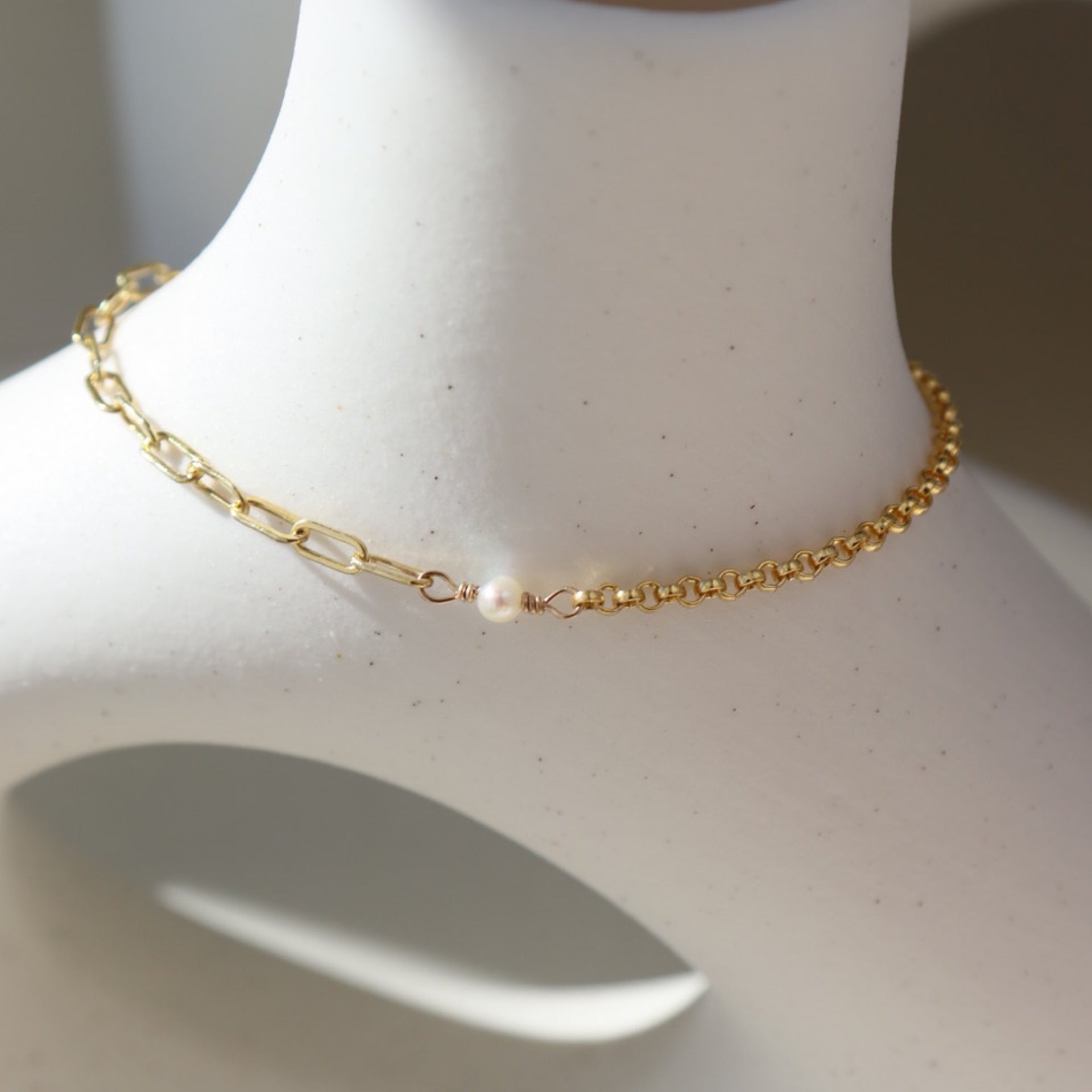 Emma bracelet set on top of a white pot. this bracelet features the narrow link chain, a tiny pearl gemstone, and the Dylan chain. The jewelry is handmade in Eau Claire Wisconsin, at Token Jewelry.