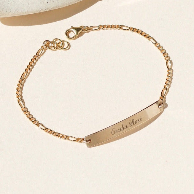14k gold fill chain and bar bracelet with custom engraving on bar on a light dish