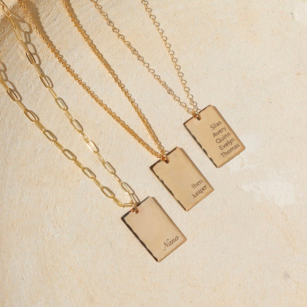 14k gold fill engraved pendants on chain necklaces on a light dish