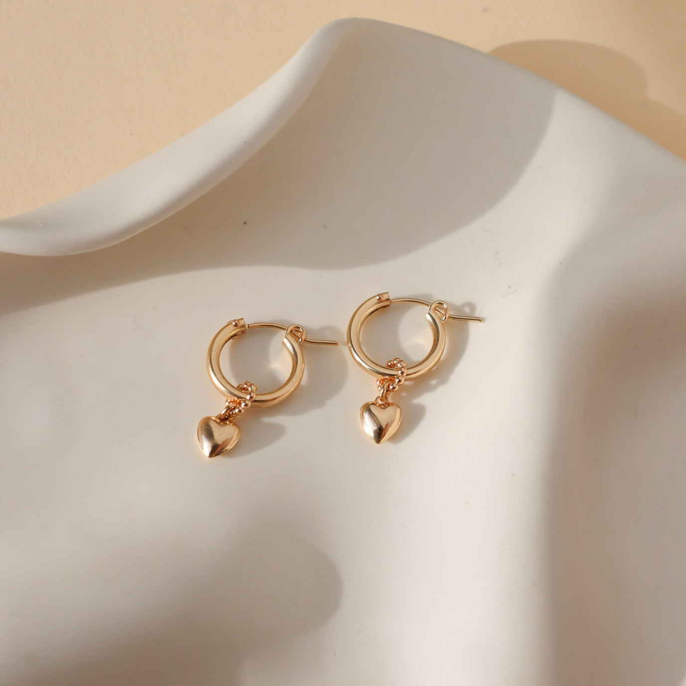 heart hoop charms on class hoops displayed on wavy plate in the sunlight