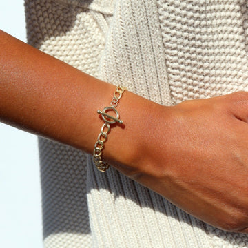 Model wearing 14k gold fill Alexandra Toggle Bracelet in the sunlight. This bracelet features the Alexandra chain with the toggle link to connect it together.