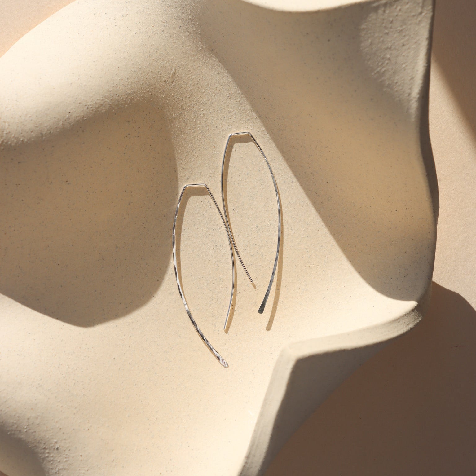 sterling silver ebb + flow slides laid on a wavy plate 