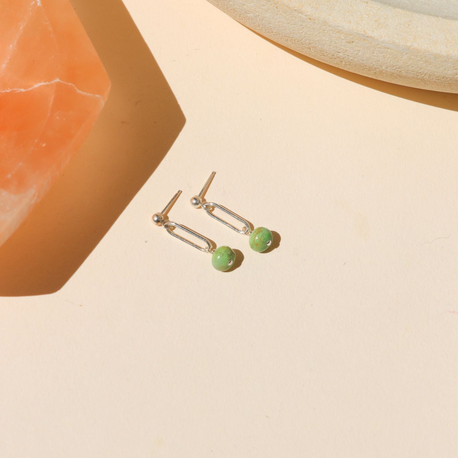 sterling silver stud earrings with turquoise bead drops on a light dish