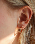 Close-up of Florence gold fill huggie  earrings on a model styled 