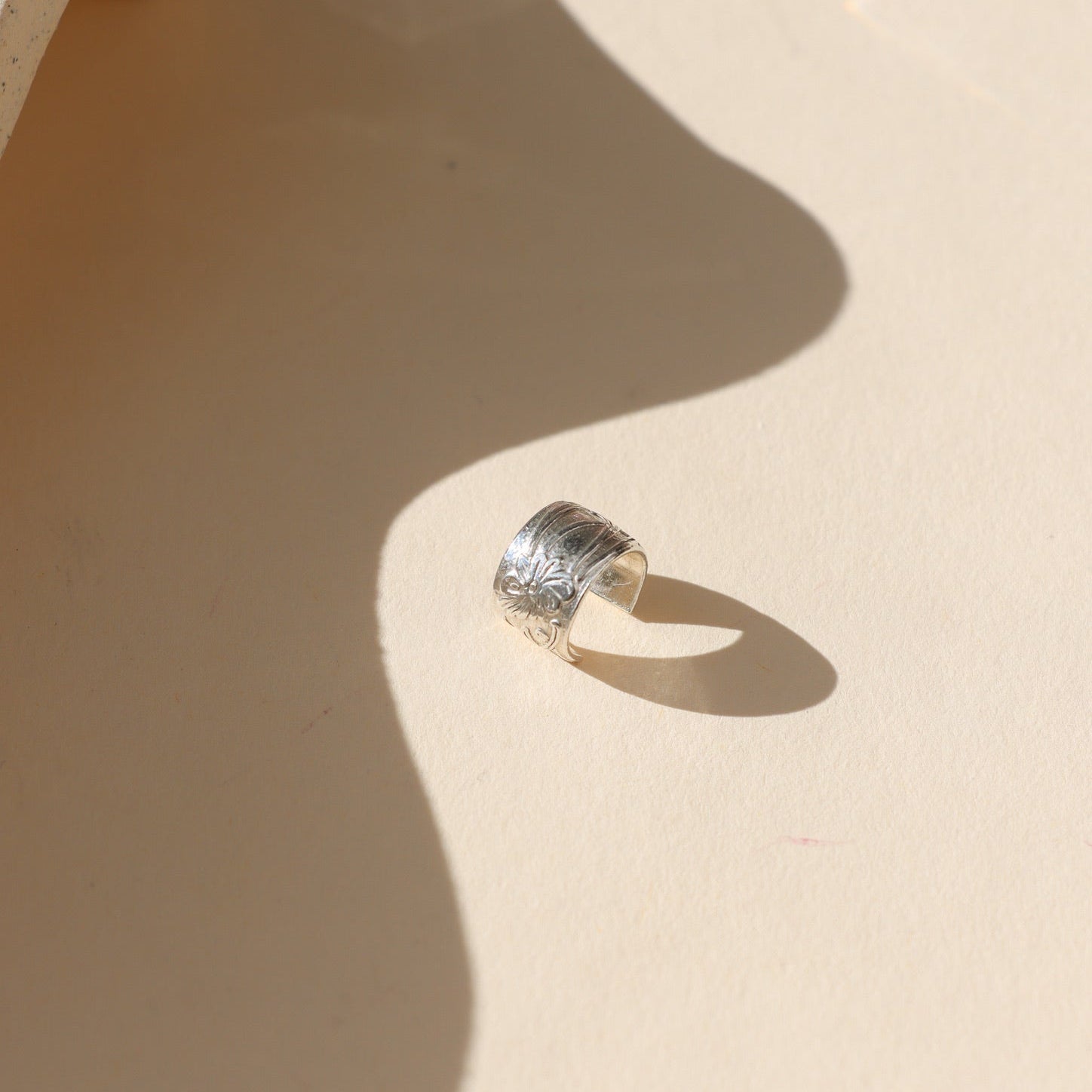 sterling silver textured ear cuff on a light background with soft shadows