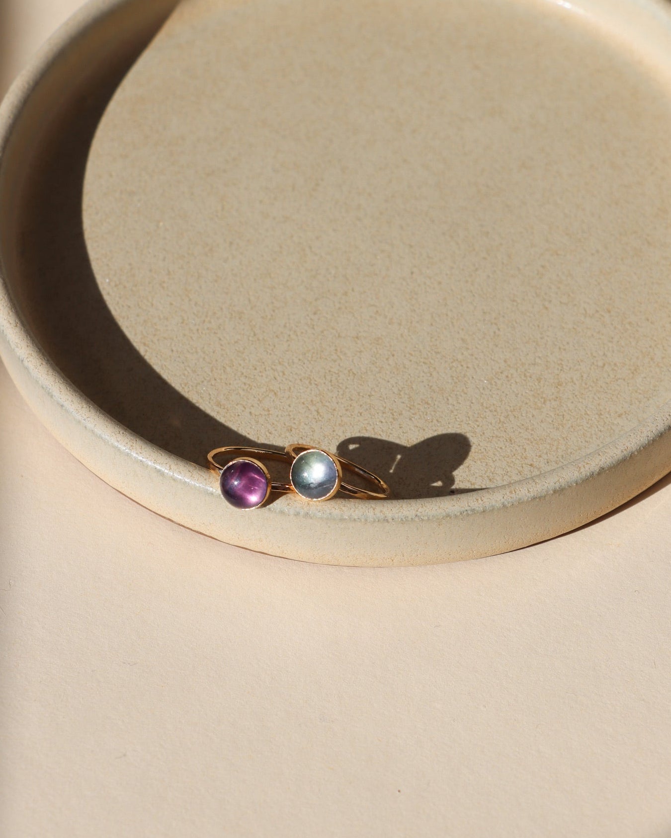 2 14k gold fill rings with round fluorite stones on a light dish
