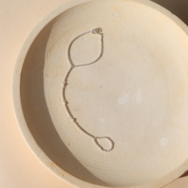 sterling silver hand chain with pearls on a light dish