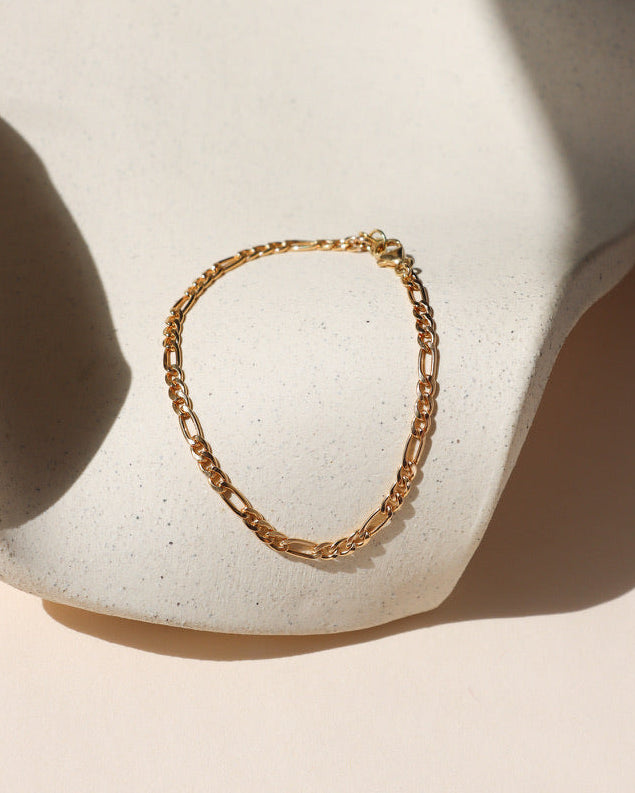 14k gold fill figaro chain bracelet on a light dish
