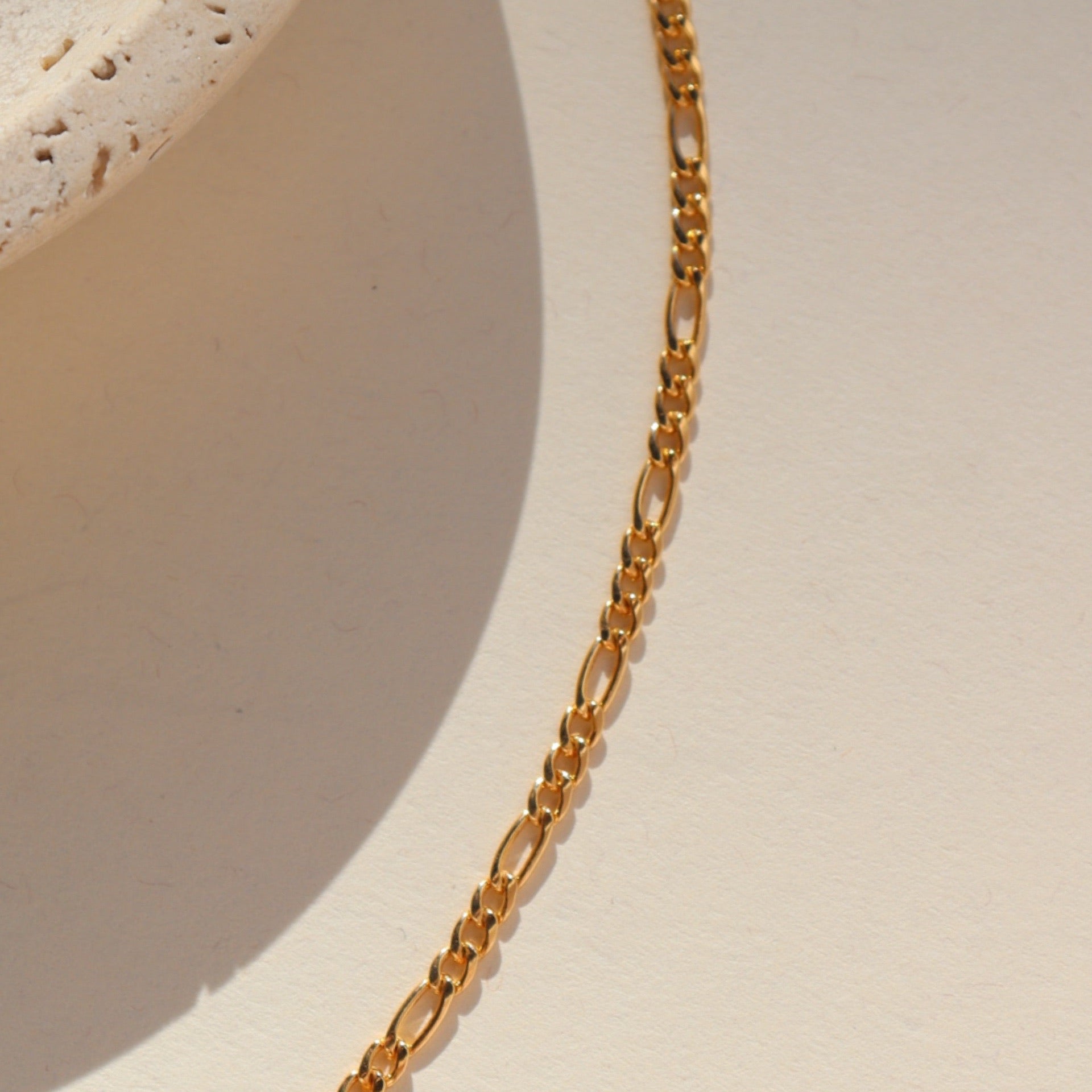 14k gold fill figaro chain bracelet on a light background