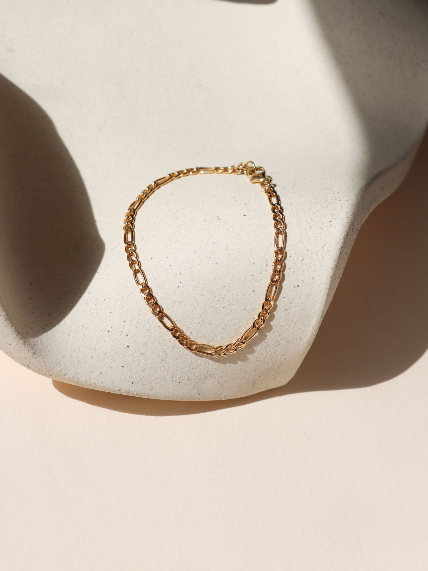 14k gold fill figaro chain bracelet on a light dish