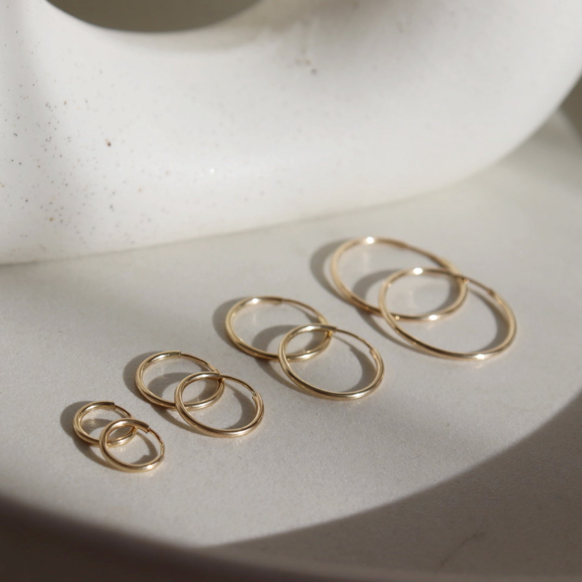 14k gold fill Goldie hoops laid on a white plate. 