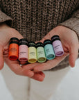 Person holding small  rainbow lip balms with labels in their hands.