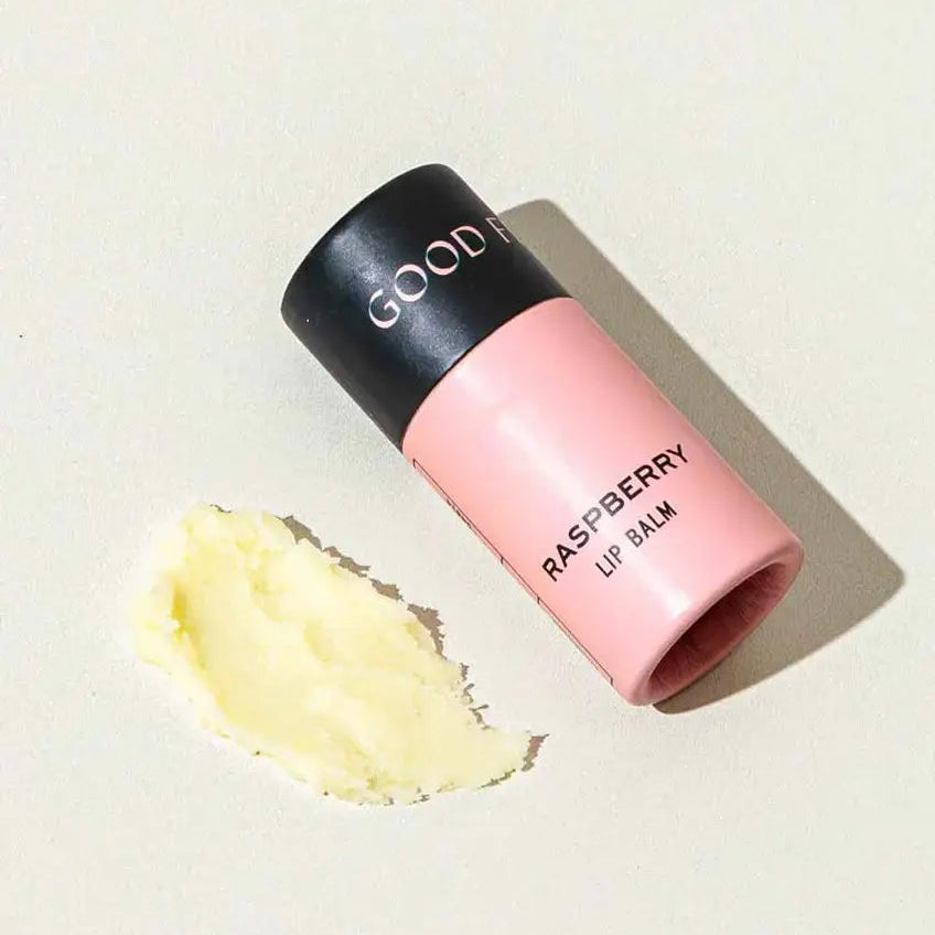 Pink lip balm with black cap on a light beige background