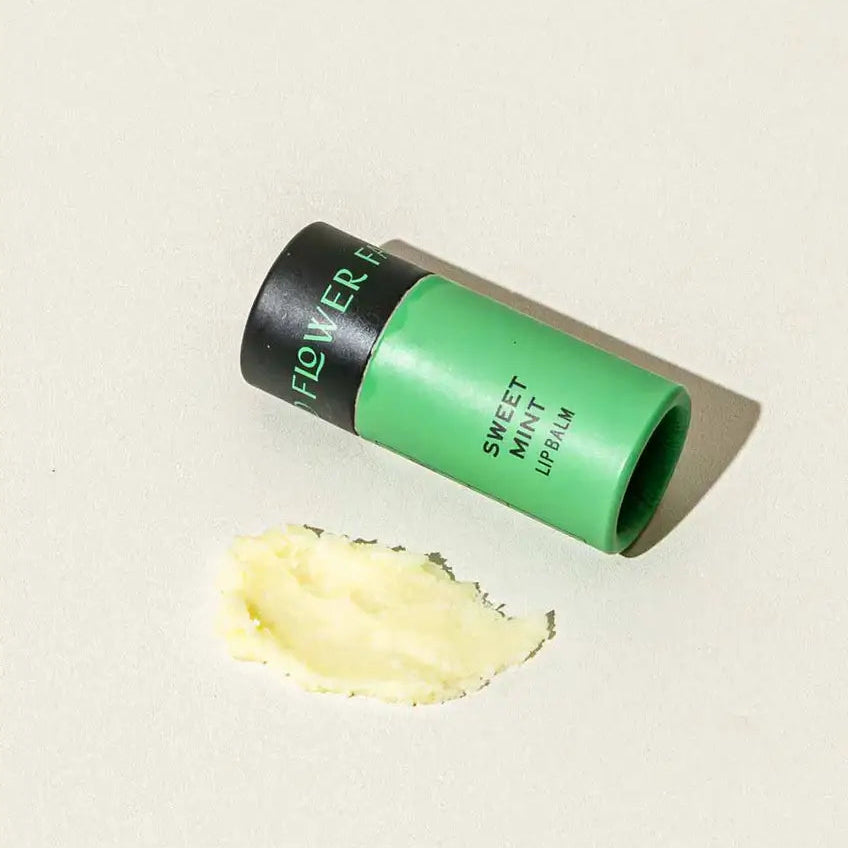 Green and black cylindrical container labeled 'Flower' with a dollop of yellow cream on a beige background