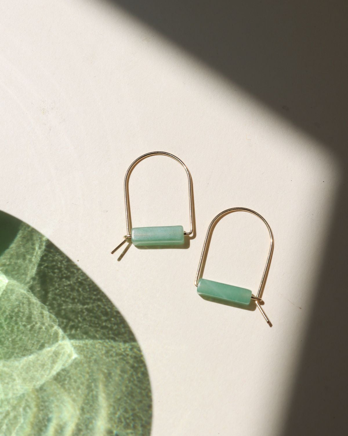 14k gold fill arch shaped earrings with aventurine tube beads on a light surface
