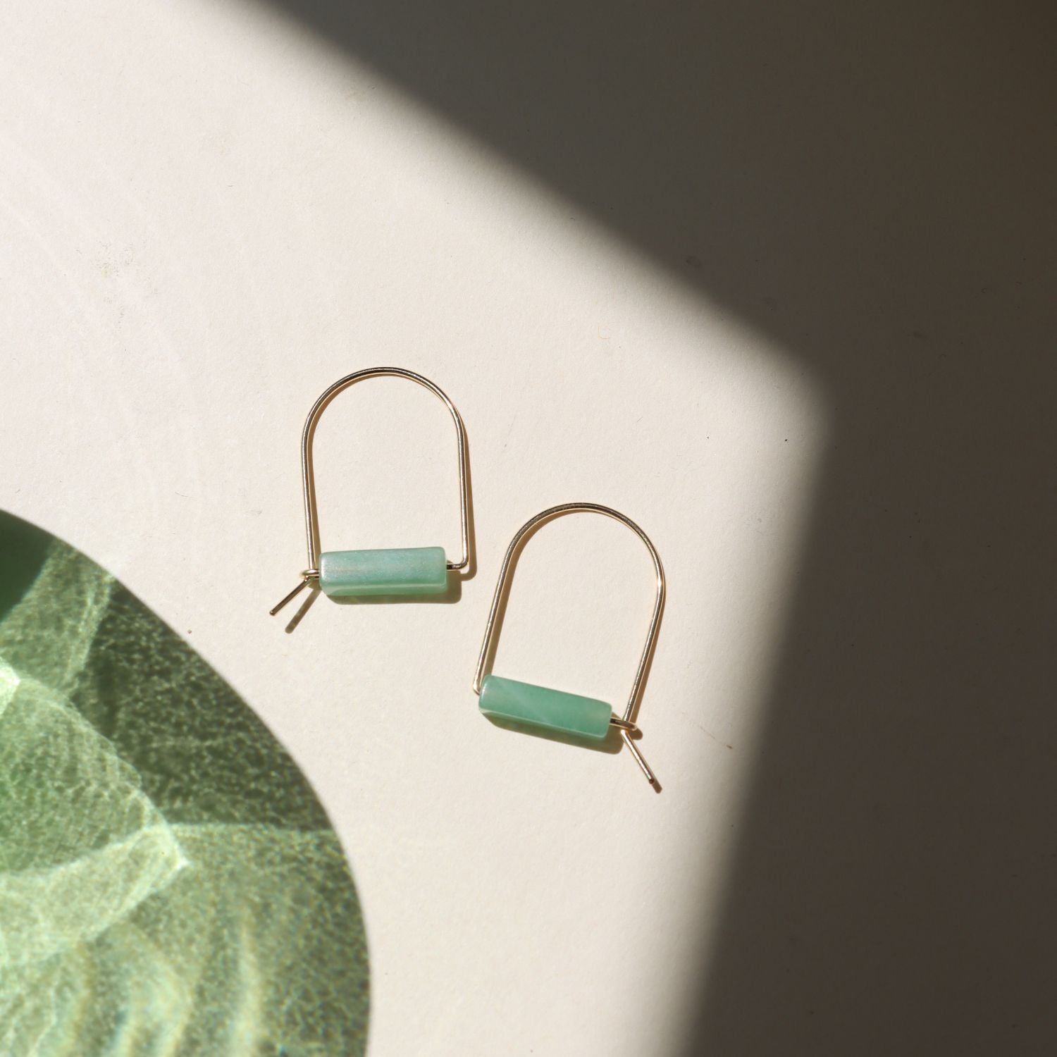 14k gold fill arch shaped earrings with aventurine tube beads on a light surface
