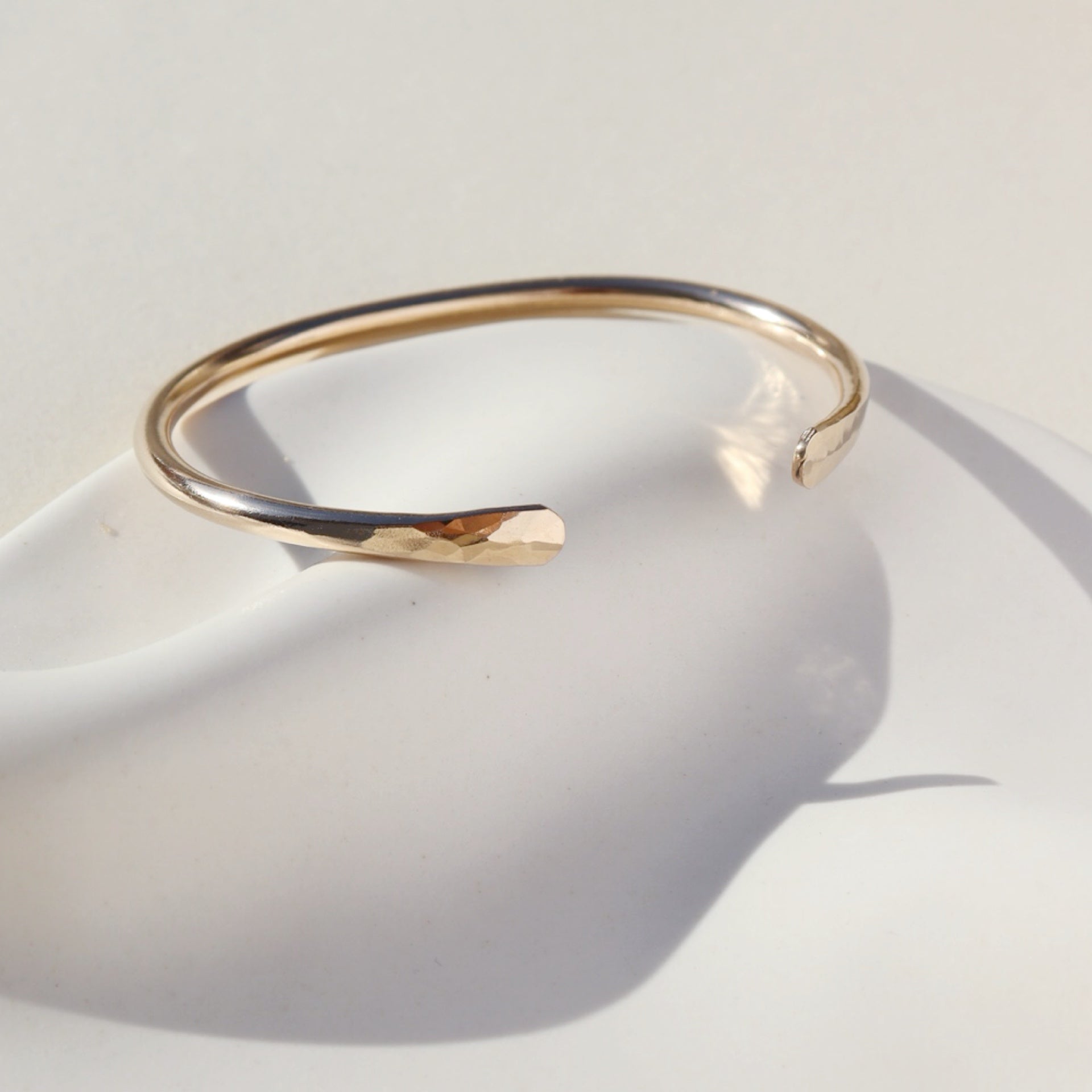 14k gold fill hammered cuff laid on white background