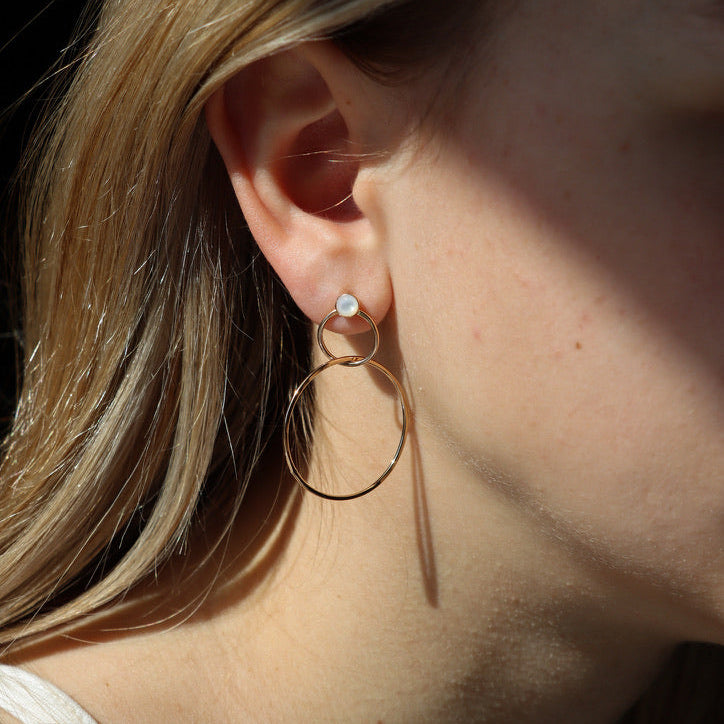 model wearing 14k gold fill pearl stud earrings with circular drops dangling down