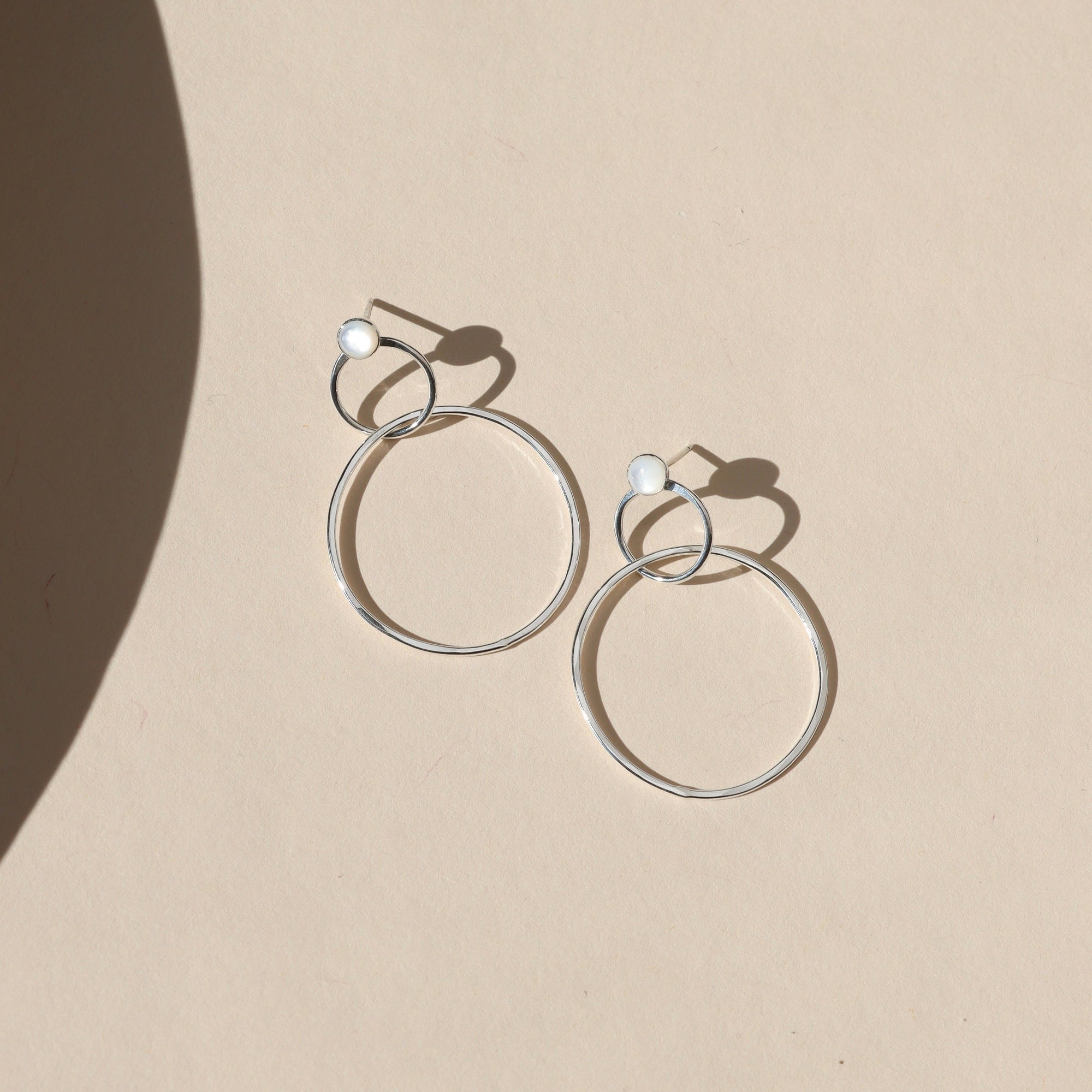 sterling silver stud earrings with handmade circle drops on a light background