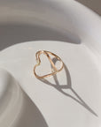 A hammered open heart shaped ring, photographed on a ceramic dish. 