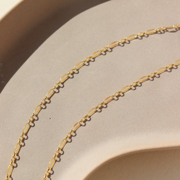 14k gold fill delicate chain, photographed on a cream colored ceramic dish