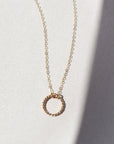 14k gold fill spiral necklace laid on a white plate in the sunlight. This necklace features the simple chain with the spiral eternity disc.