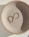 14k gold fill horseshoe earrings laid on a gray plate.