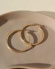 14k gold fill large classic hoop earrings for everyday, photographed on a ceramic dish