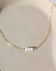 three freshwater pearls lined up on a 14k gold fill simple chain, made by Token Jewelry , photographed on a white ceramic dish