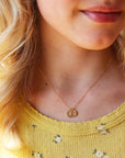 Model wearing 14k gold fill Tiny Monogram Disc Necklace. This necklace features our simple chain with a disc pendent with a heart stamped on it.