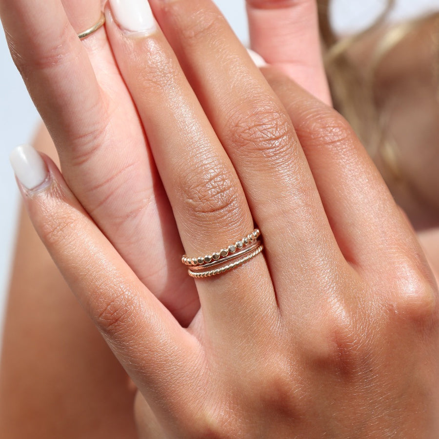Model wearing 14k gold fill SoHo Ring Set on the middle finger. This Ring set highlights each one of our go to stacking rings including the stacking ring, spiral ring, and sequins ring. These rings are made to live in made to wear everyday.