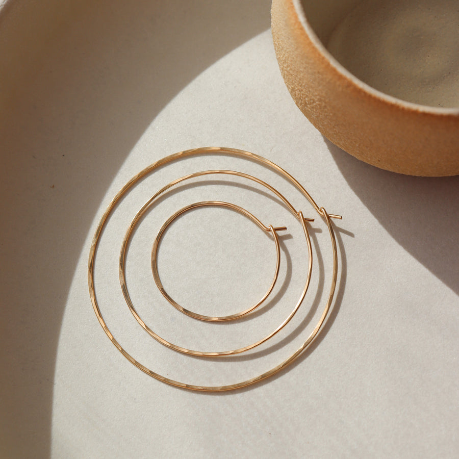 14k gold fill organic hoops placed in the sunlight 