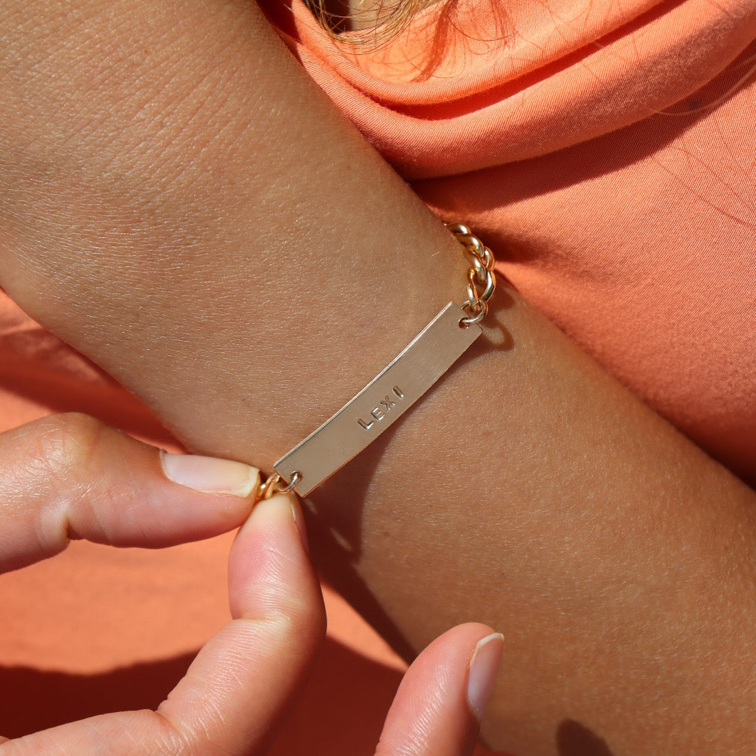 Model wearing 14k gold fill Name plate bracelet with Alexandra chain. This bracelet features a simple plate you can choose to have hammered or have smooth. This bracelet is then connected with the Alexandra chain. With this bracelet it features the option of adding a name or not.