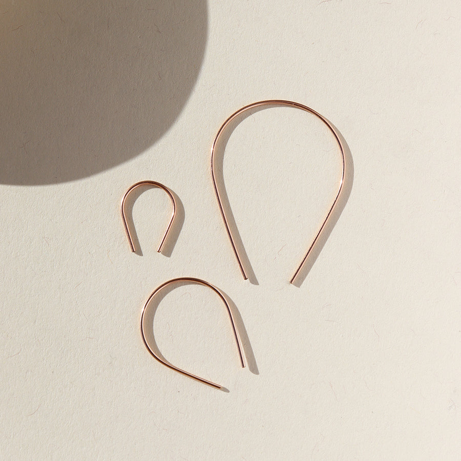 14k rose gold fill horseshoe shaped earrings photographed on a ceramic dish, handmade by Token Jewelry