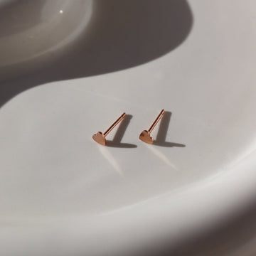 14k rose gold fill tiny heart stud earrings photographed on a ceramic dish