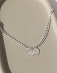 925 sterling silver Modern Muse initial Necklace in sterling silver laid on a gray plate in the sunlight. This necklace feature the Carter chain with the choice of adding on an initial charm.