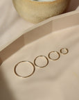 14k gold fill goldie hoop earrings placed on a peach plate