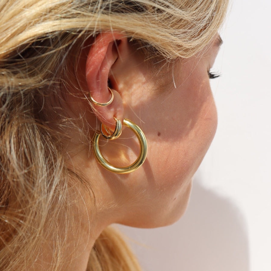 Model wearing 14k gold fill Harper hoops. These earrings feature a classic smooth hoop with a post making the easy to take in and out.