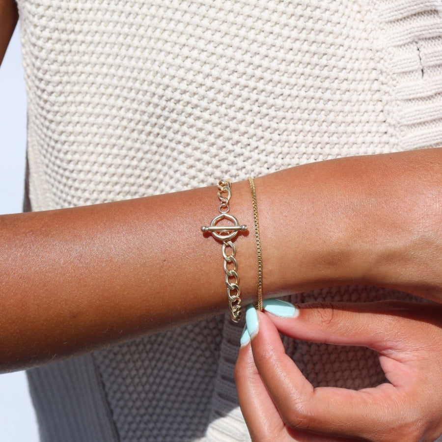 Model wearing 14k gold fill Alexandra Toggle Bracelet in the sunlight. This bracelet features the Alexandra chai with the toggle link to connect it together.