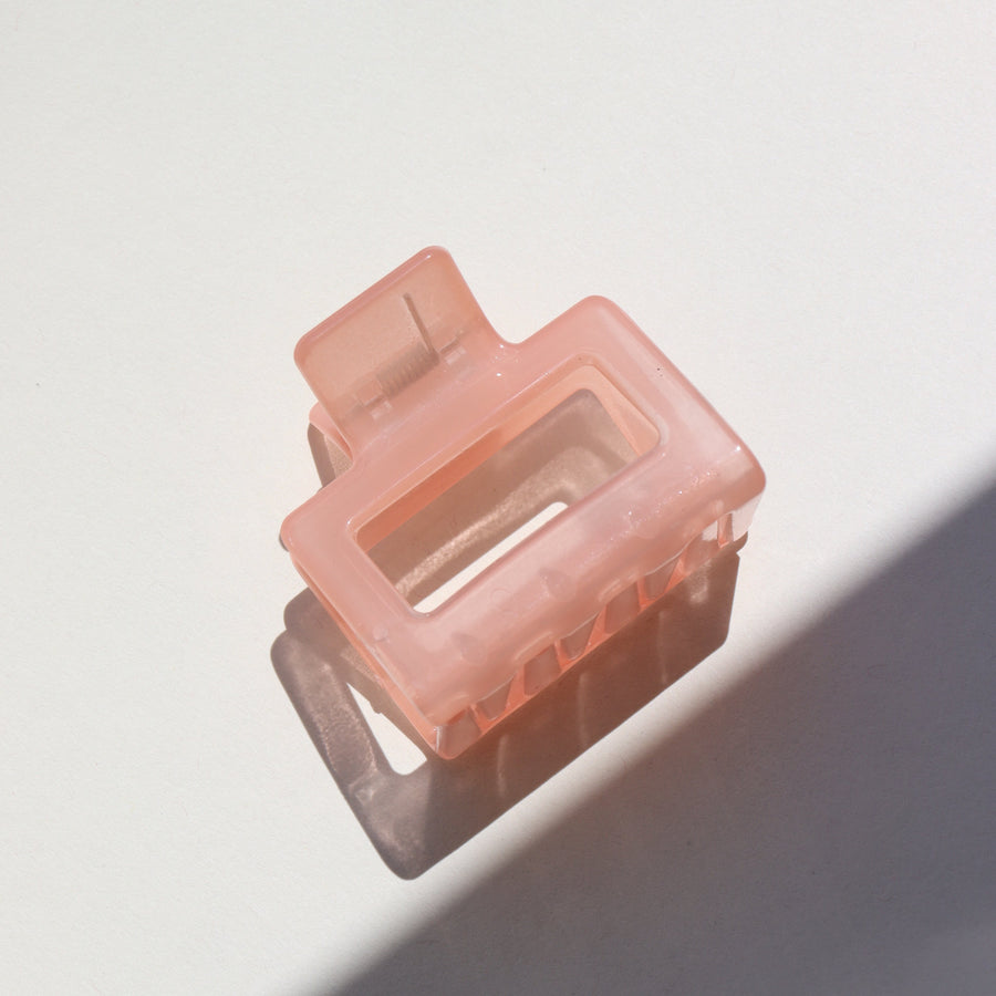 Pink grapefruit jelly Claw Clip laid on a white jewelry dish in the sunlight. 