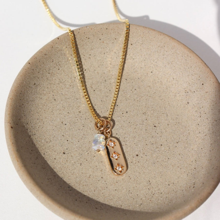 14k gold fill Orion Necklace laid on a tan plate in the sunlight