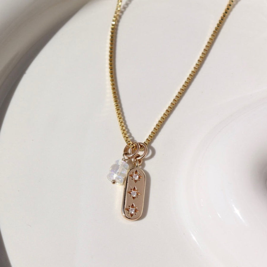 14k gold fill Orion Necklace laid on a white plate in the sunlight