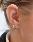 Model wearing 14k gold fill cross stud earrings. Along with the classic Goldie  hoops. 