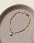 14k gold fill Peruvian Opal Bracelet laid on a tan jewelry display in the sunlight.