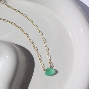 14k gold fill Sea Green Necklace placed on a white plate in the sunlight. This Necklace feature our Cosette Chain which is a paperclip chain. This chain is then connected with a green chalcedony gemstone.