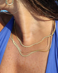 14k gold filled herringbone chains layered look on a model in the water.