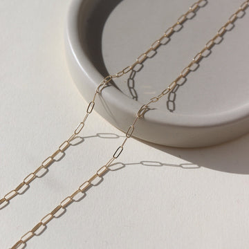 14k solid gold delicate link chain, photographed on a ceramic dish