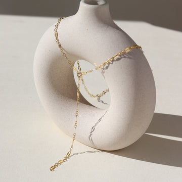 14k gold fill lariat chain, photographed on a cream colored ceramic dish