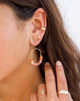 Gold hoop earrings with colorful beads on a beige background taken on a model